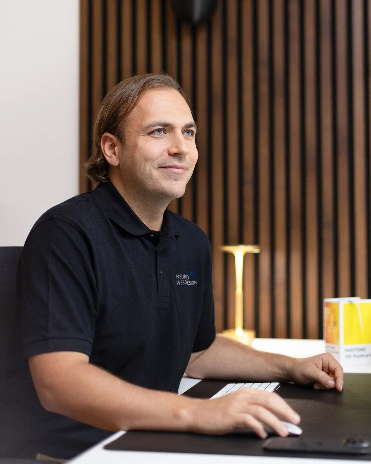 Jonas Reggelin am Schreibtisch, eine Hand an der Maus, der Blick zur Seite